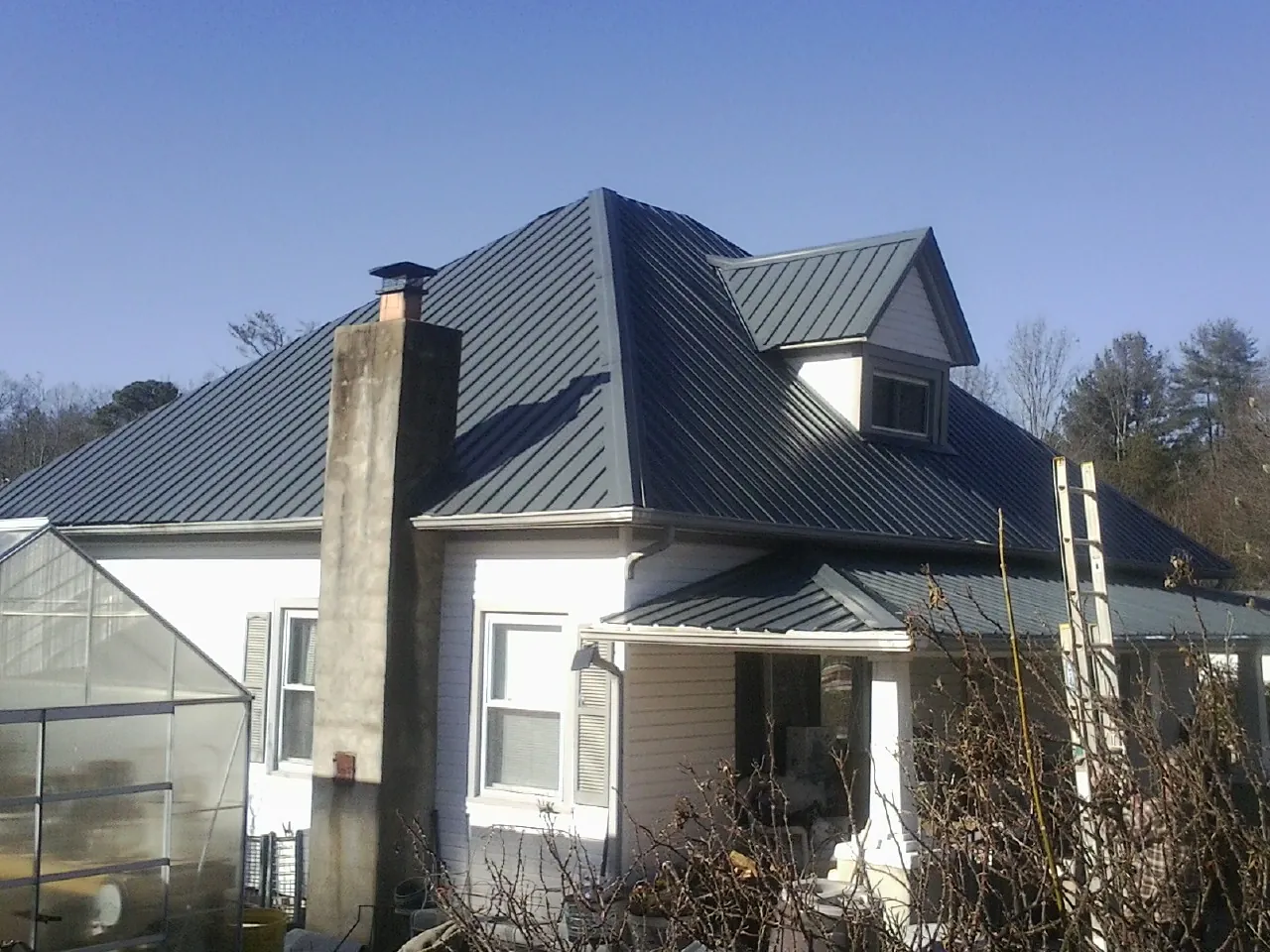 Dark blue standing seam metal roof on a white farmhouse with dormer — Slate & Tile Roof Repair by Roofing Brothers in Millbury