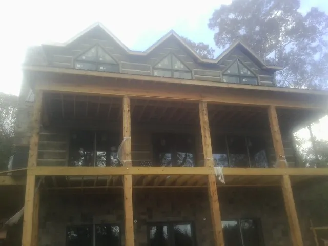 Dormers and porch framing on a large log home under construction — Roof Coating work by our crew in Millbury