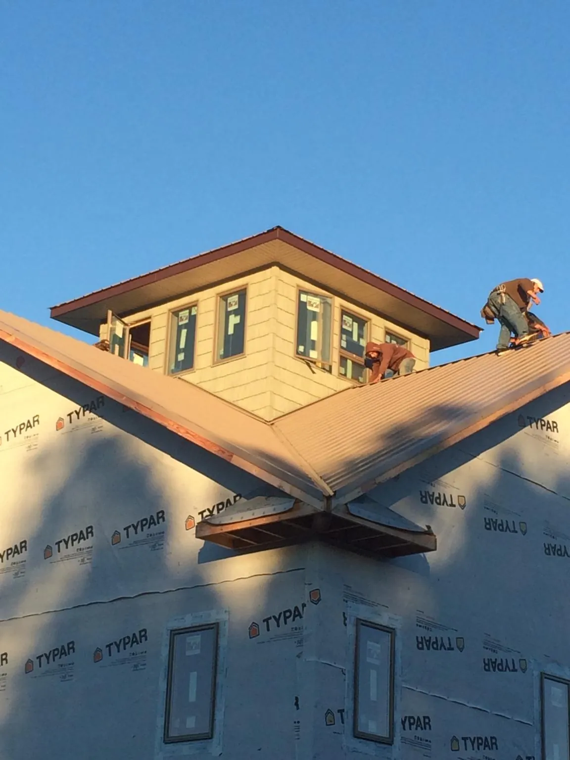 Roofers working around a rooftop cupola on a new metal roof at sunset — Roof Waterproofing in Millbury by Roofing Brothers